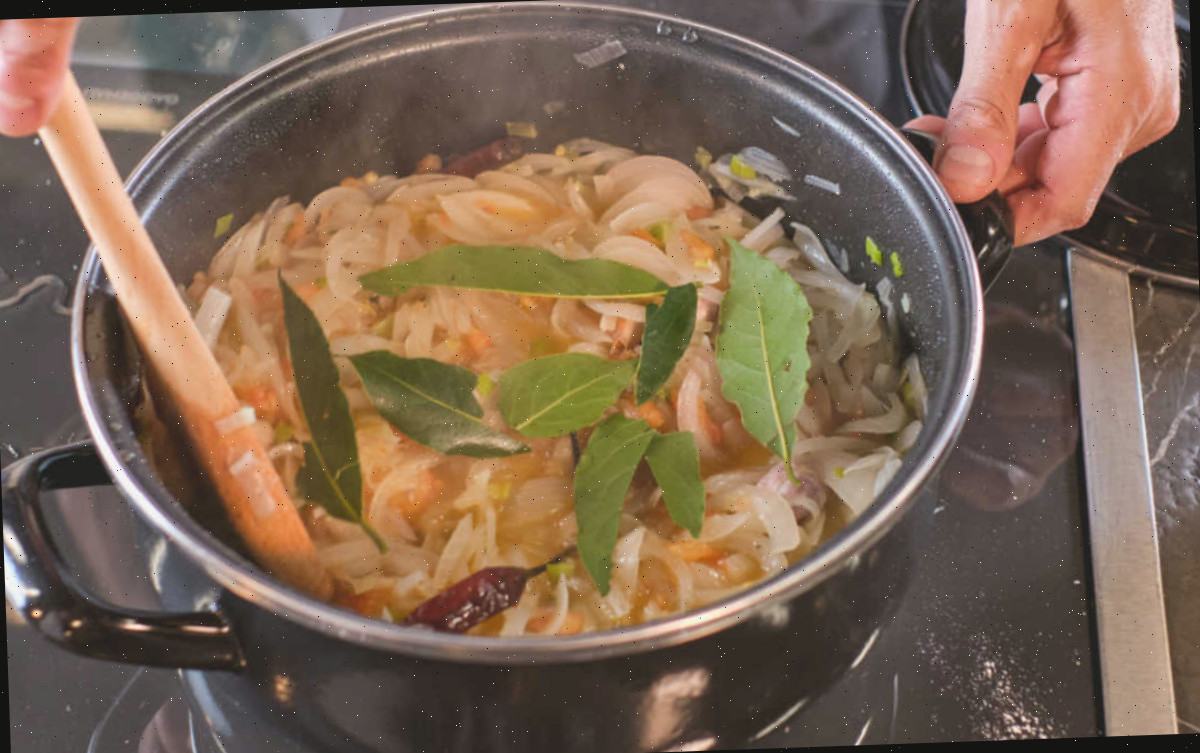 Utilizando folhas de louro na culinária. Mãos segurando uma panela de massa com algumas folhas de louro adicionadas.
