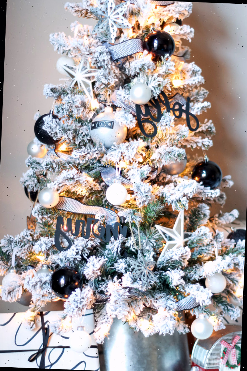 Árvore de Natal de mesa coberta de neve com ornamentos em preto e branco