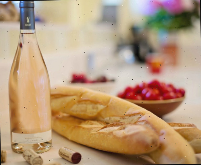 Baguete fatiada, tomates e uma garrafa de vinho.