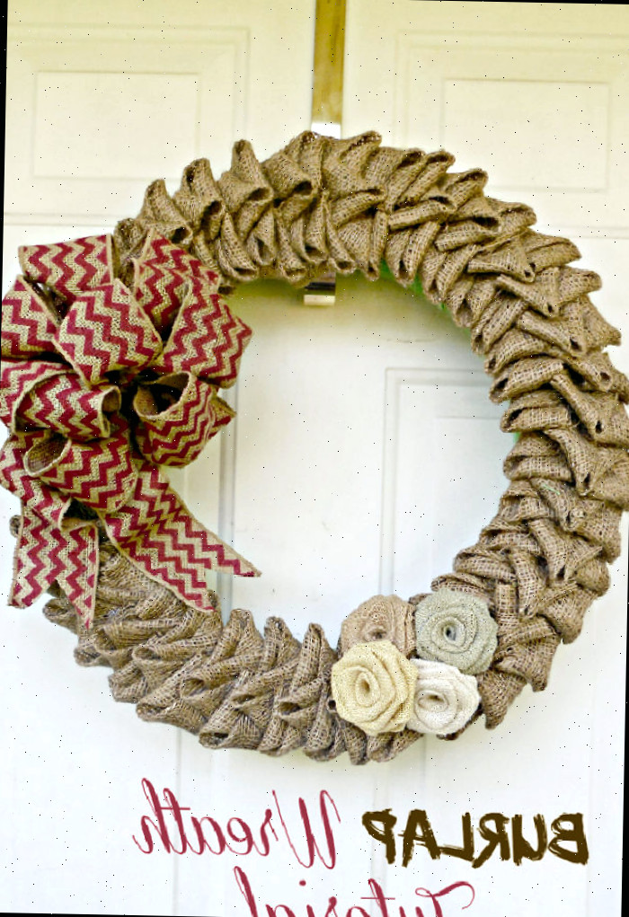 Uma guirlanda de flores de juta com laço listrado em laranja pendurada em uma porta. Texto lê Tutorial de guirlanda de juta.