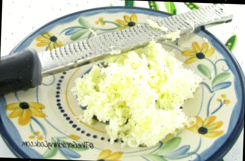 Manteiga ralada em um prato floral ao lado de um microplane.