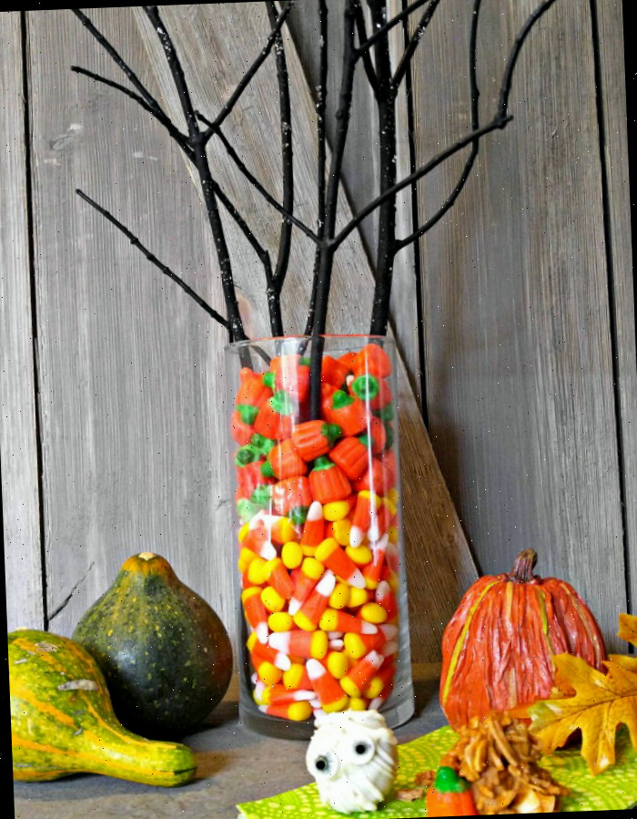 centro de mesa com doce de milho e galhos escuros com abóboras Centro de mesa com doce de milho e delícias de Halloween