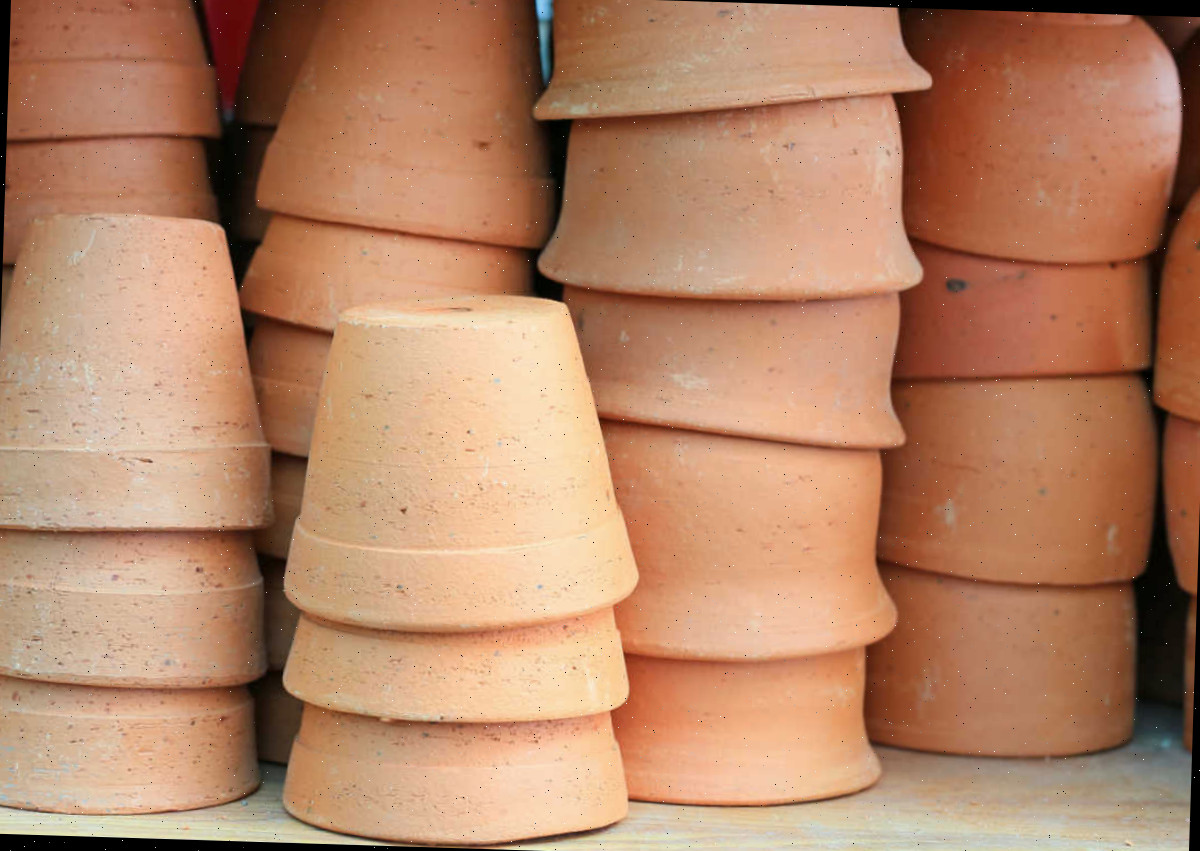 Vasos de barro limpos empilhados sobre uma prateleira de madeira.