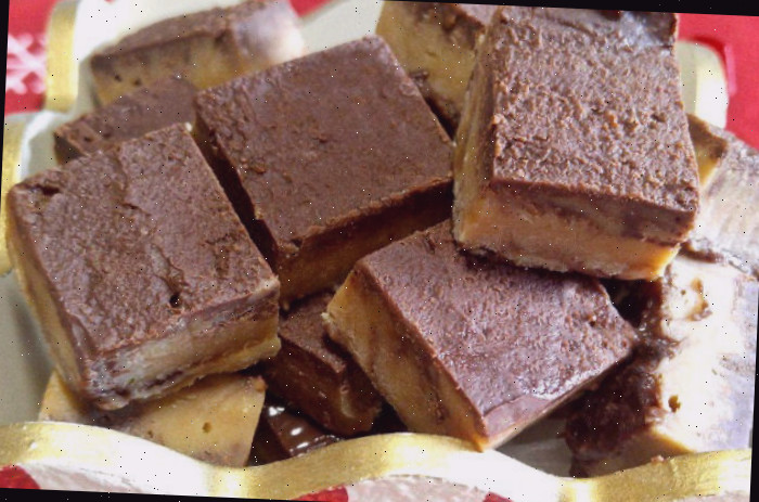 fudge perfeito fudge perfeito cortado em quadrados em uma caixa listrada de vermelho e branco.