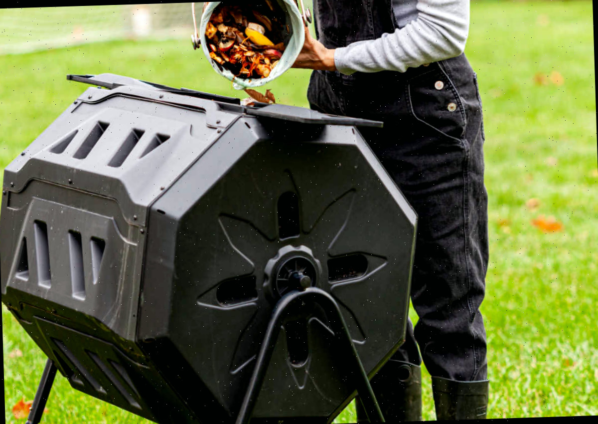 Uma mulher inserindo resíduos de cozinha em um compostor giratório para criar um corretivo de solo através do composto.