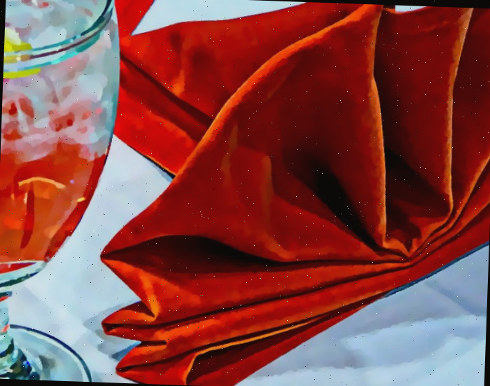 Guardanapo de veludo vermelho dobrado e bebida com um coquetel vermelho.