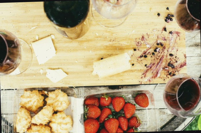 Tábua de corte com taças de vinho e frutas.