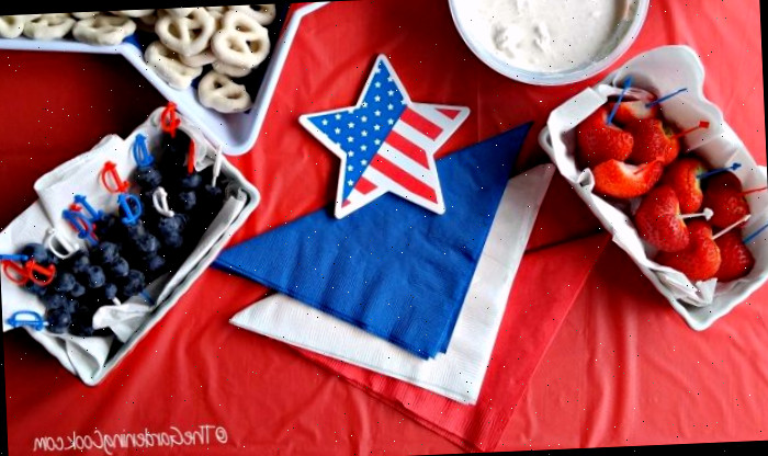 Morangos, mergulho, pretzels de iogurte e mirtilos com estrela de bandeira e toalhas vermelhas, brancas e azuis.