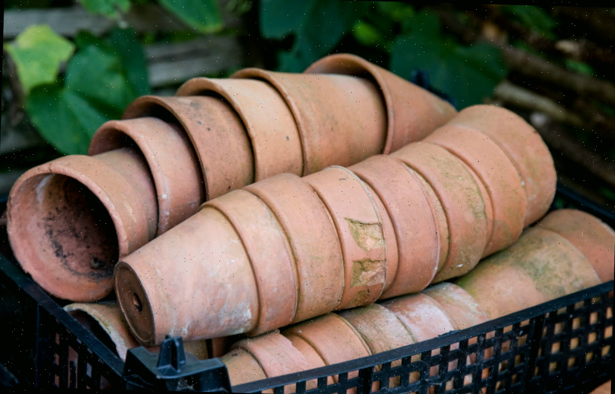 Montes de vasos de terracota sujos em uma caixa preta.