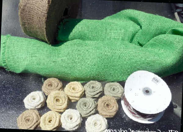 Materiais para fazer uma guirlanda de juta DIY - juta verde, fita com borda de arame e fileiras de flores de rosa de juta.