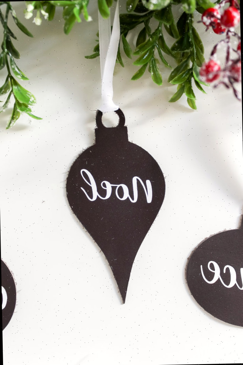 Ornamento de couro Noel sobre mesa branca com vegetação