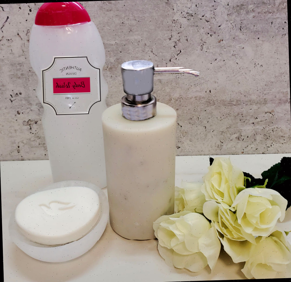Use como sabonete líquido para as mãos ou como gel de banho. Detergente líquido DIY em dispensadores de gel de banho e de sabonete para as mãos ao lado de uma barra de sabão Dove e algumas rosas brancas.