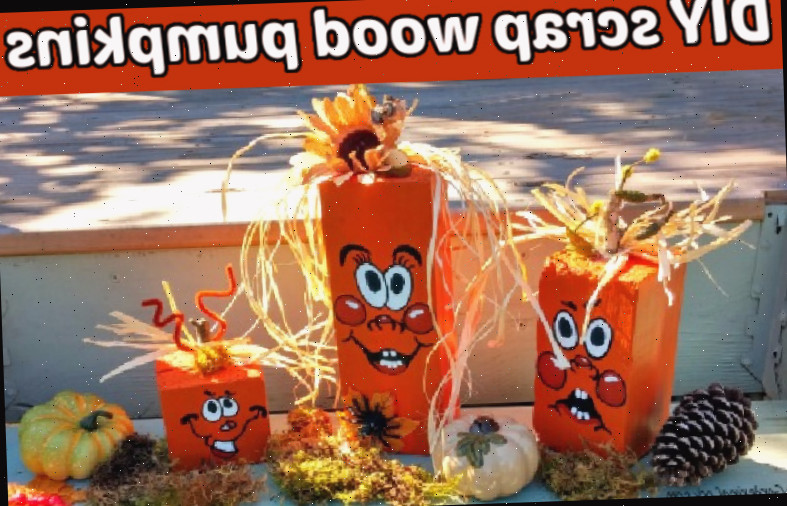 Três blocos de madeira recuperada pintados de laranja com rostos pintados à mão, flores e palha para decorar, ao lado de pinhas, folhas e mini abóboras.