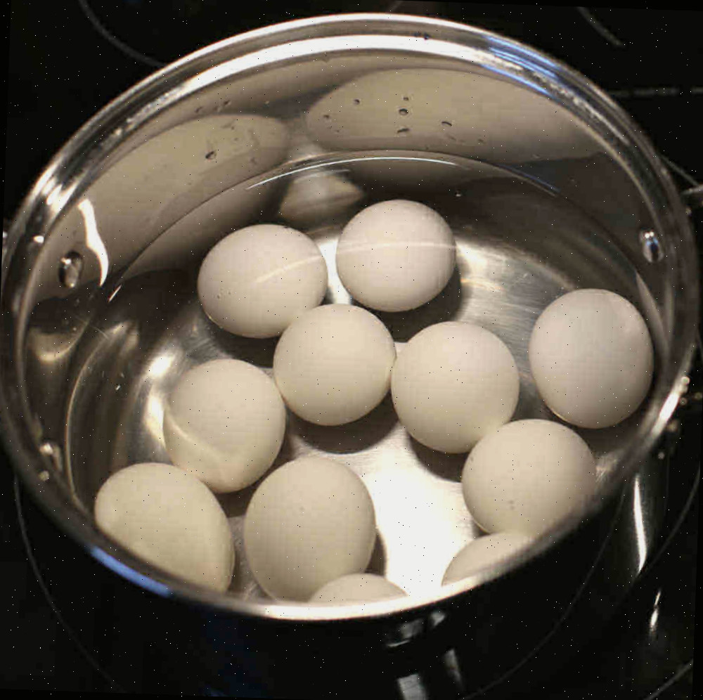 Comece com água fria. Ovos em uma panela com água fria em um fogão preto.