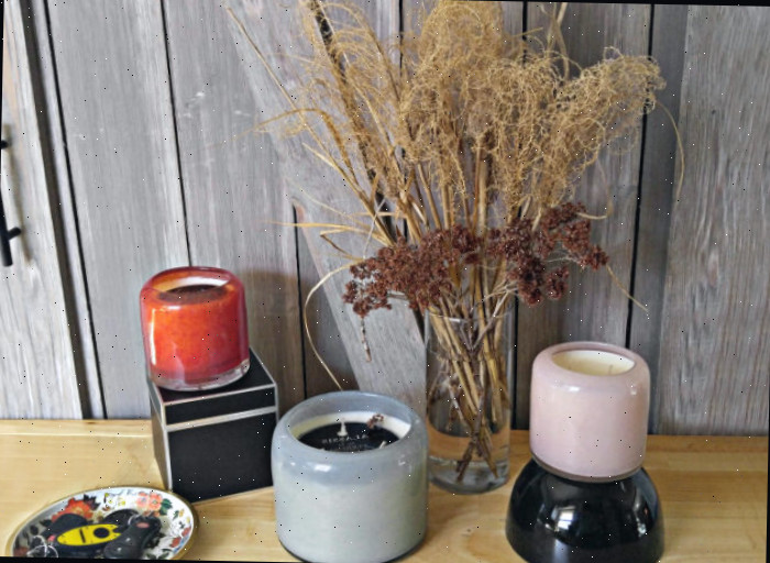 Três velas ao lado de um vaso de flores secas e uma bandeja com chaves para decorar a entrada com velas.