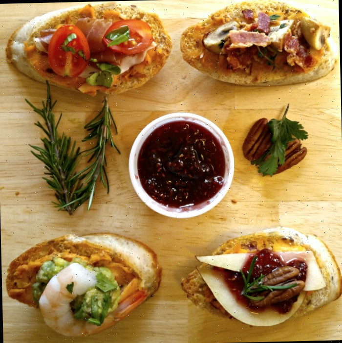 Aperitivos de crostini em uma tábua de madeira com alecrim, nozes e molho.