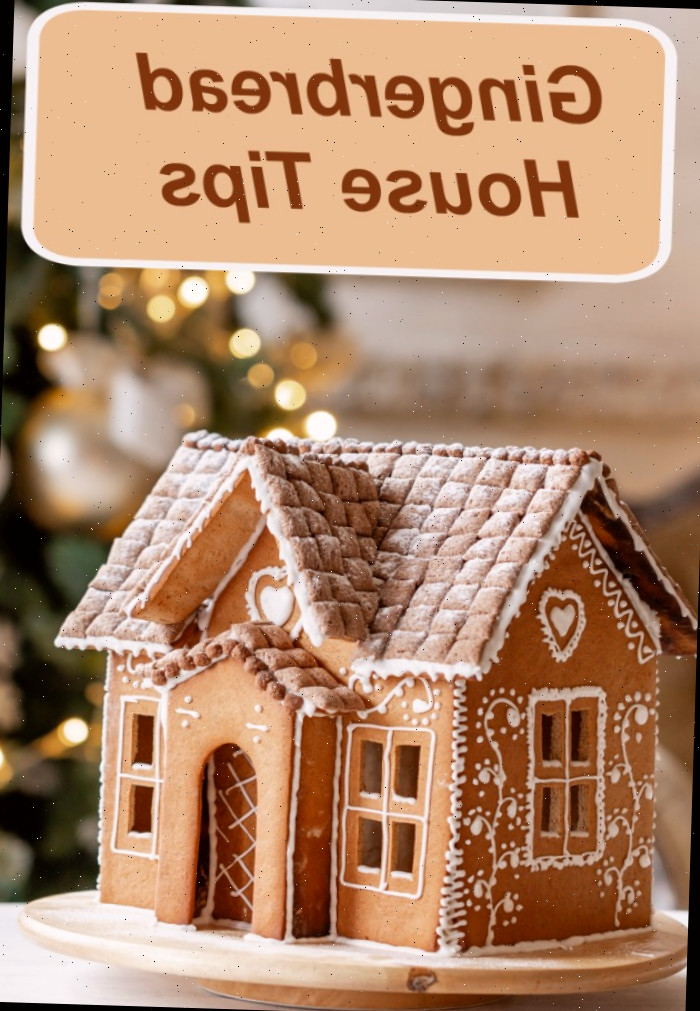 Uma casa de gengibre decorada sobre um prato giratório com glacê branco perto de uma árvore de Natal, com palavras dizendo dicas para casa de gengibre.