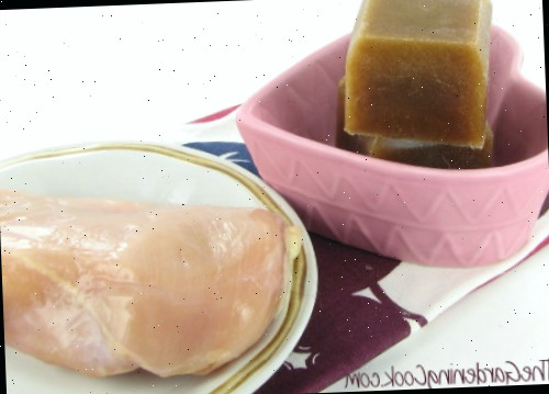 Cubo de molho congelado Molho congelado sobrante feito nas formas de gelo de silicone próximo a um frango cru.