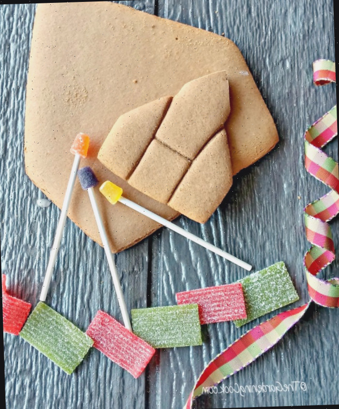 Fita, doces, pedaços de gengibre e postes de luz de gelatina sobre uma tábua de madeira.