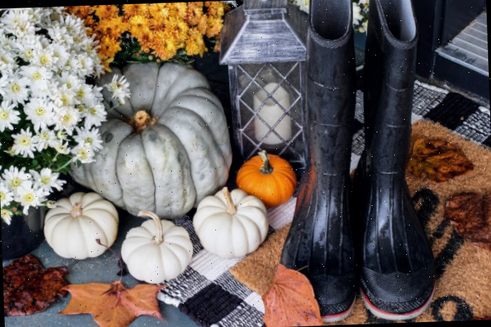 Decoração de folhagem de outono com flores, botas, lanternas e abóboras heirloom.