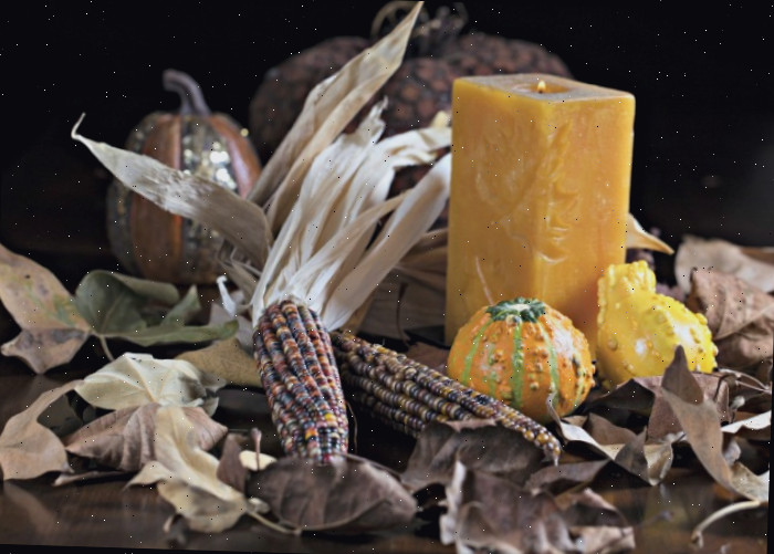 Exposição de milho indiano na mesa. Exposição de milho indiano para uma mesa usando uma vela em bloco e abóboras em tom amarelo e espigas e folhas de milho marrons contrastantes.
