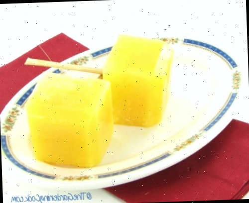 picolés de suco de laranja picolés de suco de laranja feitos em formas de gelo de silicone em um prato branco e azul com um guardanapo vermelho.