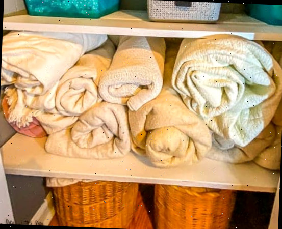 enrolar cobertores e toalhas para a organização do pequeno armário de roupas de cama