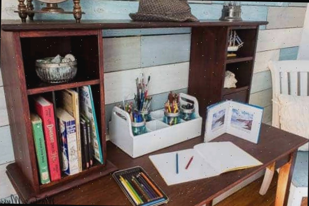 Mesa de trabalho de mogno com material de desenho e livros