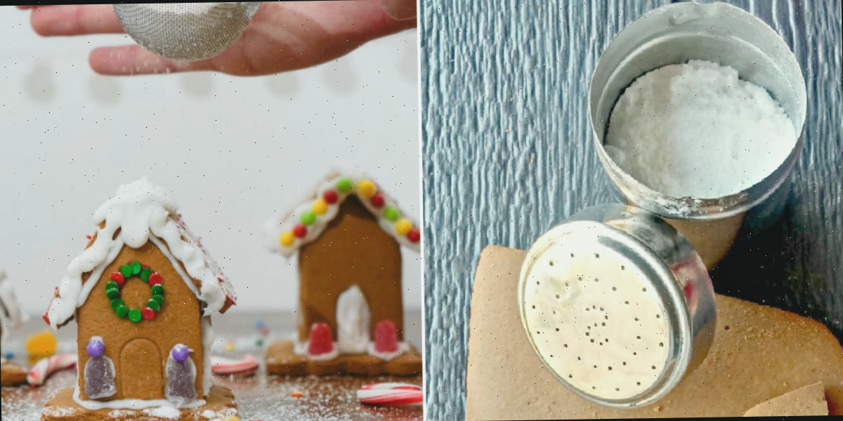 Uma peneira para farinha cheia de açúcar de confeiteiro ao lado de uma mulher segurando uma peneira com açúcar de confeiteiro sobre uma casa de gengibre para fazer neve.