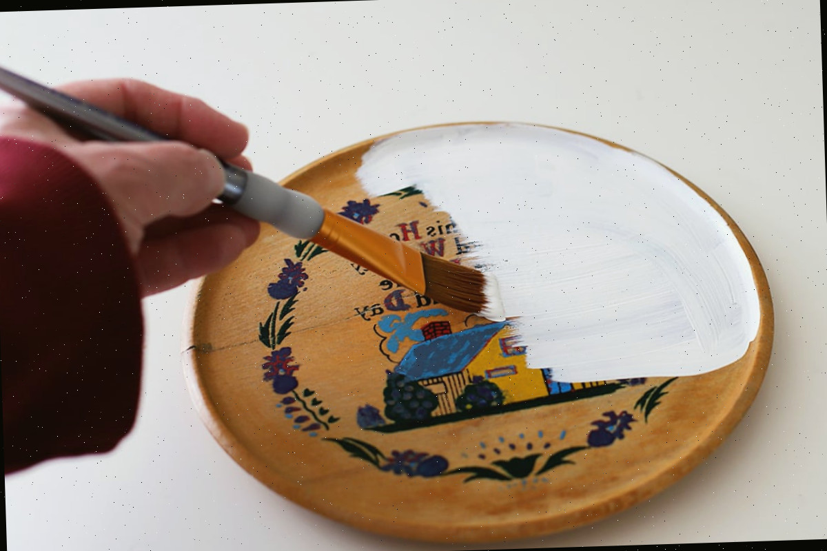 Pintando uma placa de madeira com tinta branca.