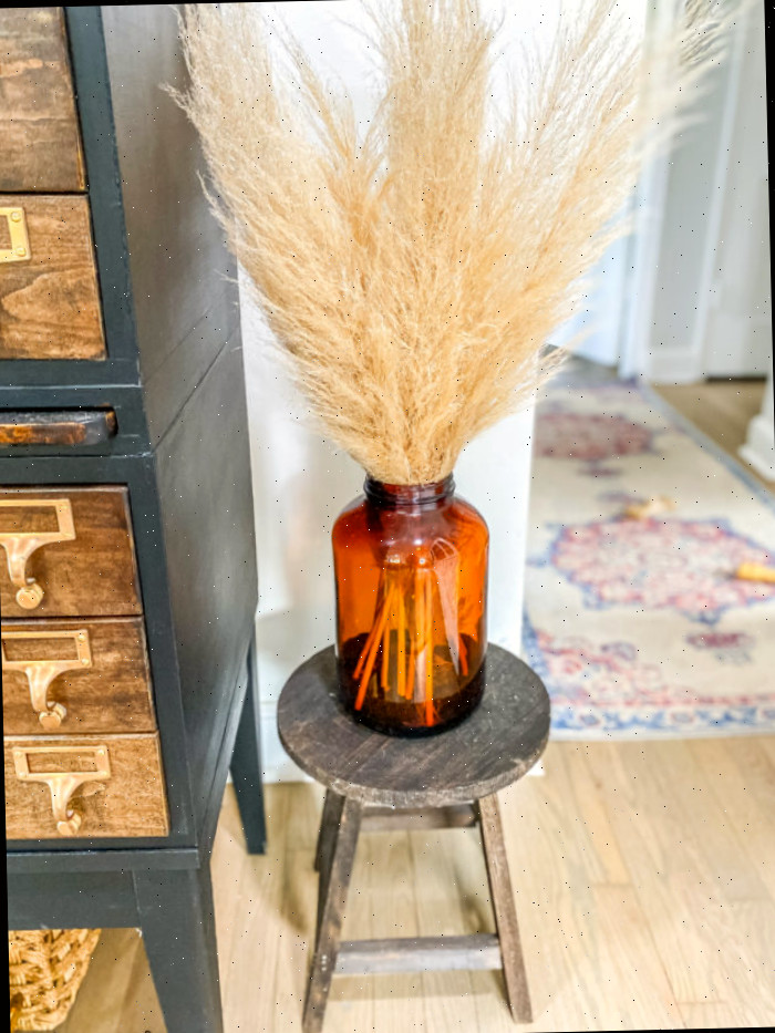 Garrafas vintage laranjas repletas de capim-da-pampas