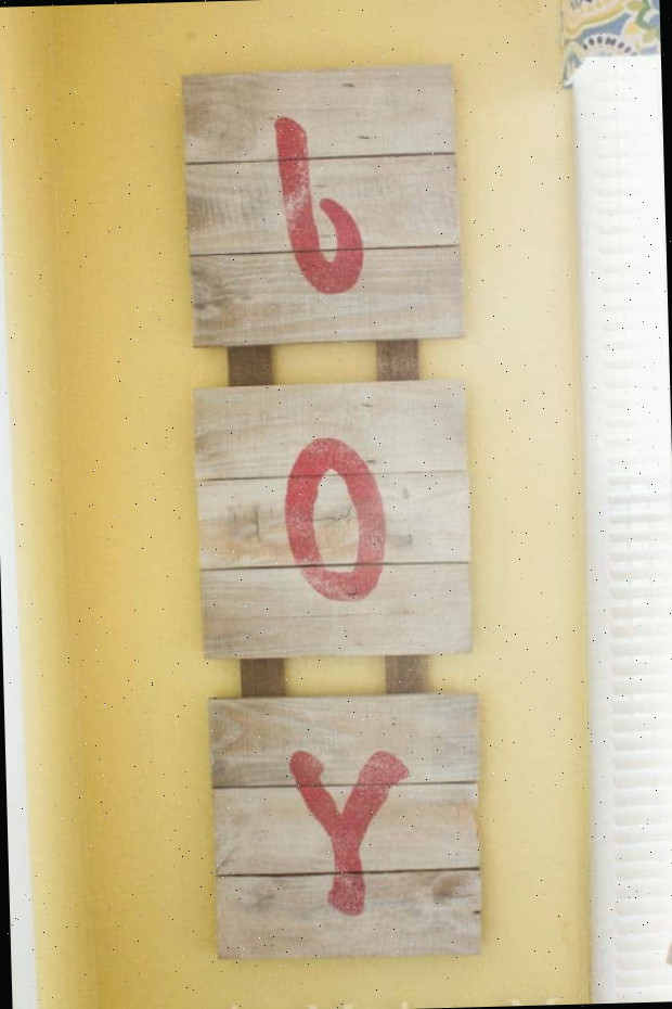 Placa de madeira com JOY em letras estêncil
