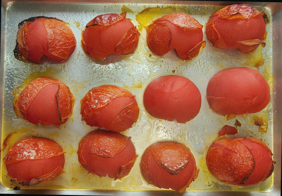 Tomates beefsteak assados em uma assadeira com cascas que se desgastaram e enrugaram.