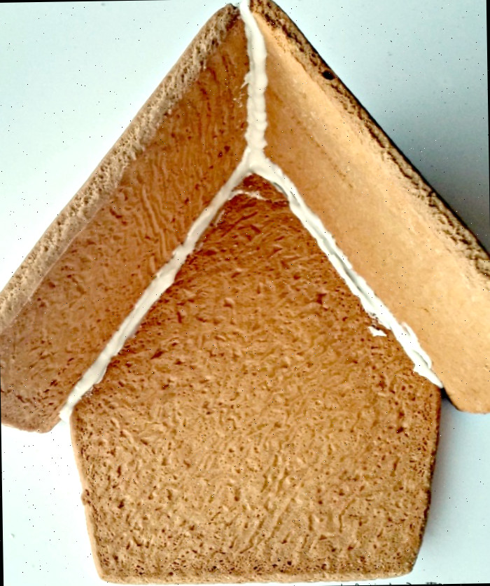 Glacê real aplicado às peças da casa de gengibre para fixar o telhado à lateral.