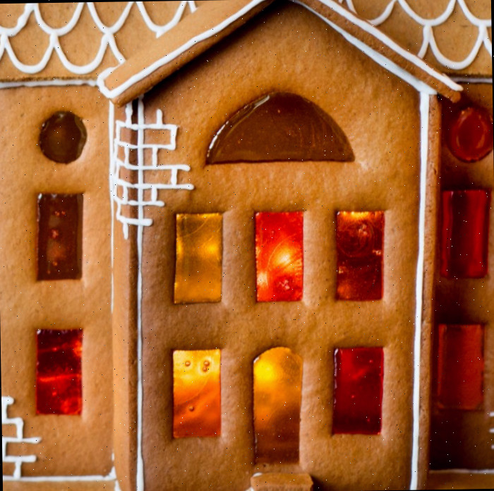 Uma casa de gengibre com glacê branco e doces derretidos usados para fazer janelas de vitral.