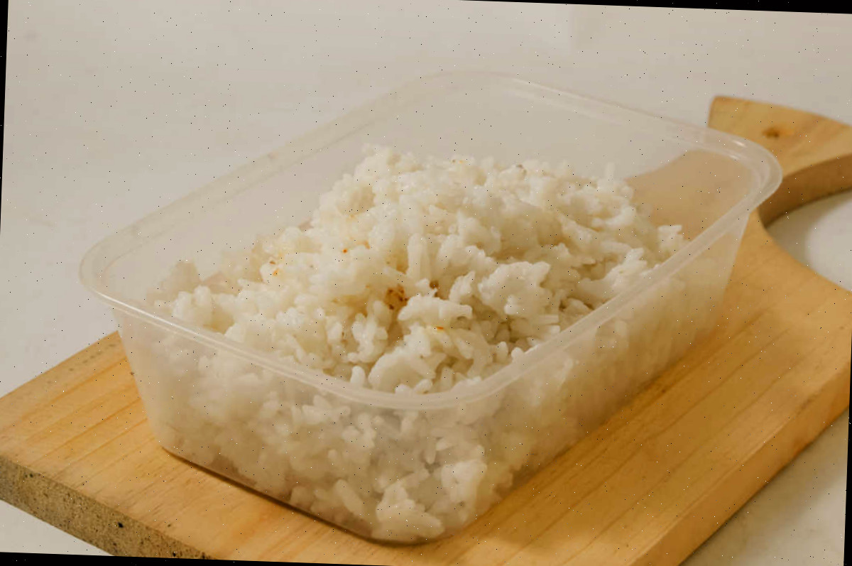 Armazene o arroz sobrando corretamente para segurança. Recipiente de arroz cozido sobrando em uma tábua de corte.