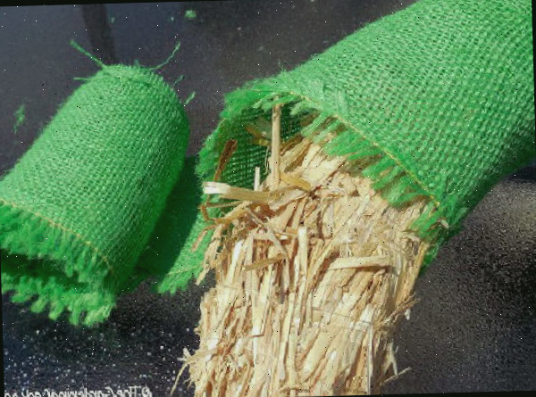 Uma guirlanda de palha coberta com juta verde ao lado de um rolo de tecido de juta verde.