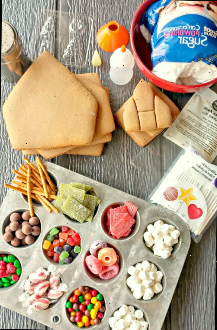 Doces em formas de muffin, componentes da casa de gengibre, uma peneira para açúcar de confeiteiro e outros materiais para fazer sua própria casa de gengibre.