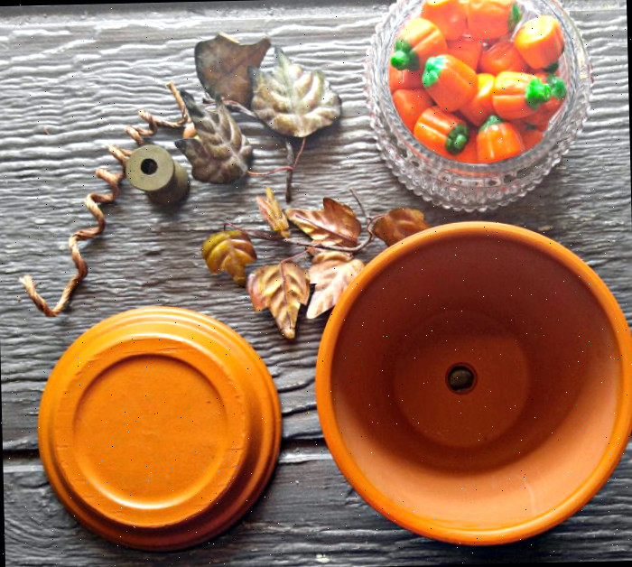 materiais para a abóbora de vaso de barro Doces de milho em um prato de vidro, carrete de madeira, cabo de arame, flores secas e um vaso de barro com seu prato.