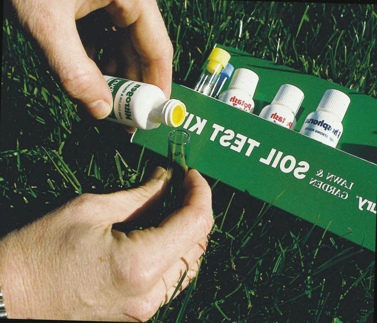 Mãos segurando um kit de teste de solo usado para avaliar o pH do solo do jardim.
