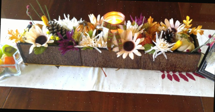 Caminho em uma mesa de madeira com caixa cheia de flores.