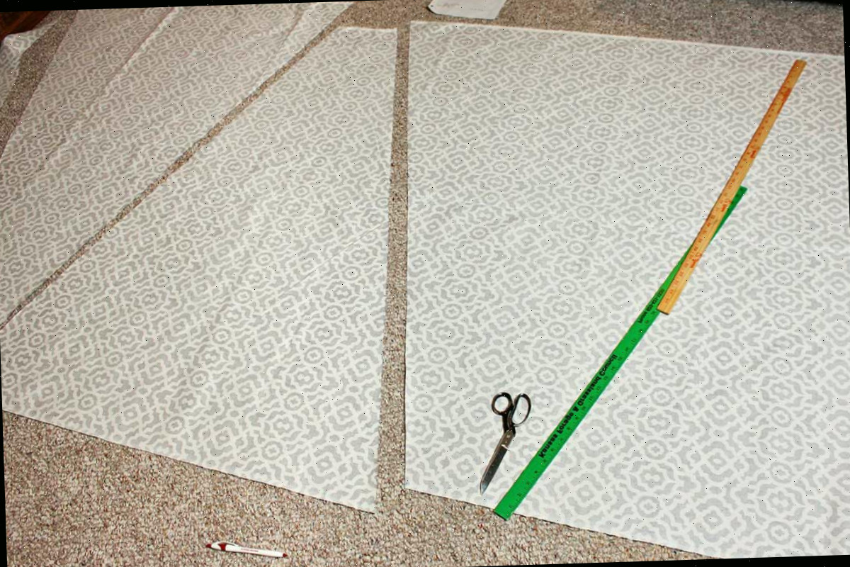Painéis triangulares para um Toldo Teepee DIY para Crianças sendo cortados de um tecido com uma tesoura de tecido, medidos com uma fita métrica.