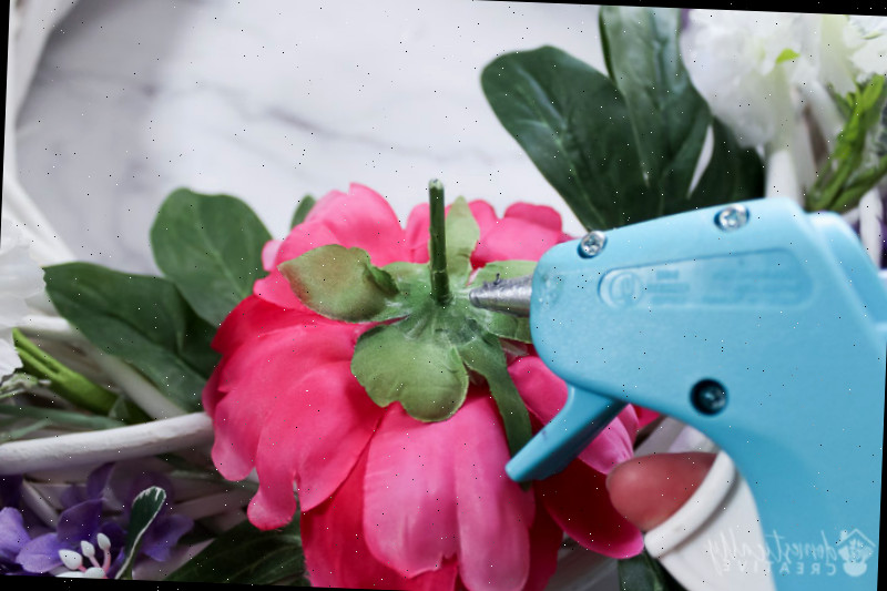 usando uma pistola de cola quente com flores de peônia para fixar na forma da guirlanda