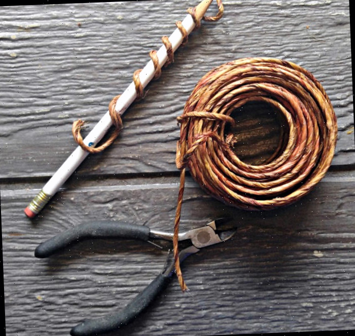 Configurando o arame Um rolo de arame ao lado de um cortador de arame e um lápis enrolado com um pedaço do arame.